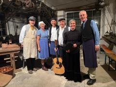 Mehrere Menschen in historischen Gewändern stehen in der alten Edelsteinschleiferei und lächeln in die Kamera.